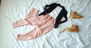 A stylish outfit laid out on a bed, featuring casual yet chic clothing and accessories in pastel hues, symbolising motherhood.