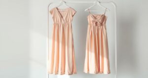 Two glamorous, elegant dresses hanging side by side in soft hues, set against a stylish backdrop.