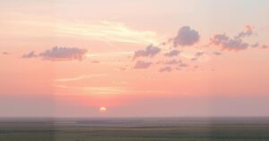 A serene landscape with soft clouds in pastel hues and a gentle sunset, symbolizing hope and remembrance.