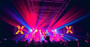 A crowded concert with colourful lights, highlighting a 'Kiss Cam' moment, abstractly symbolizing relationship drama.