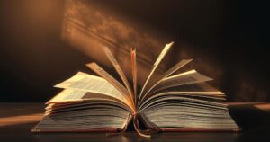 An open book with pages turning, surrounded by shadows and light, symbolizing the journey of reclaiming identity.