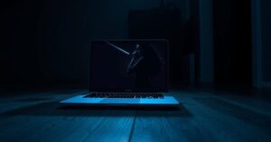 A dimly lit room with a laptop screen and a silhouette of a glamourous model, reflecting online interactions.